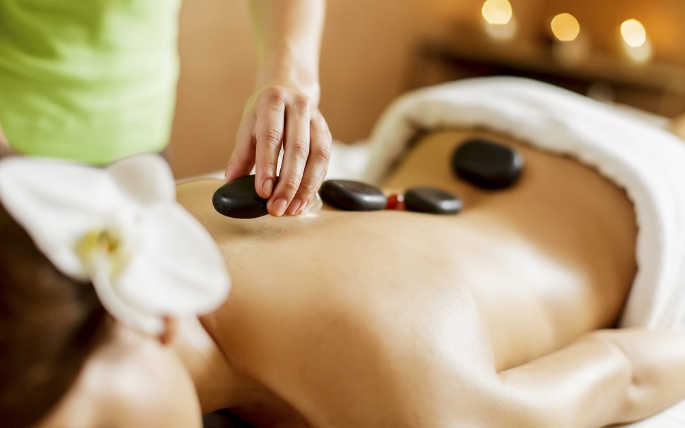 Person receiving a relaxing hot stone massage, with smooth stones placed along their back 