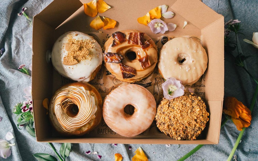 A delicious assortment of The Salty Donut's one-of-a-kind flavors, featuring various creative toppings and fillings.