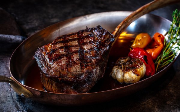 Cooked steak served with a whole roasted garlic an peppers, elegantly plated