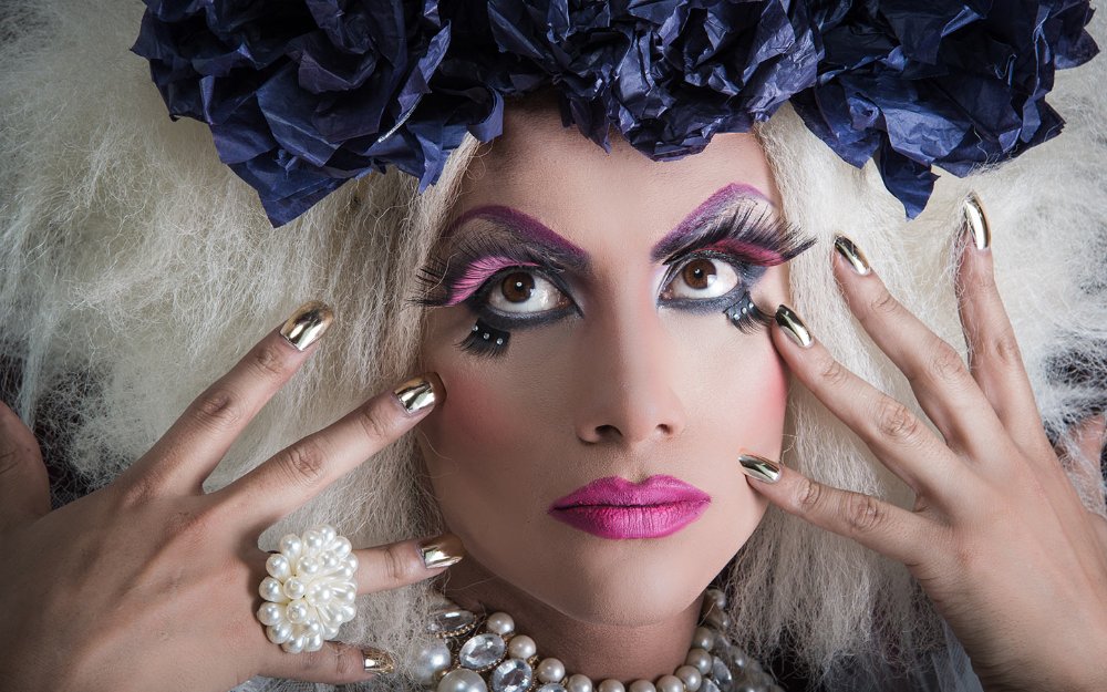 A drag queen shown with makeup and nails in the image